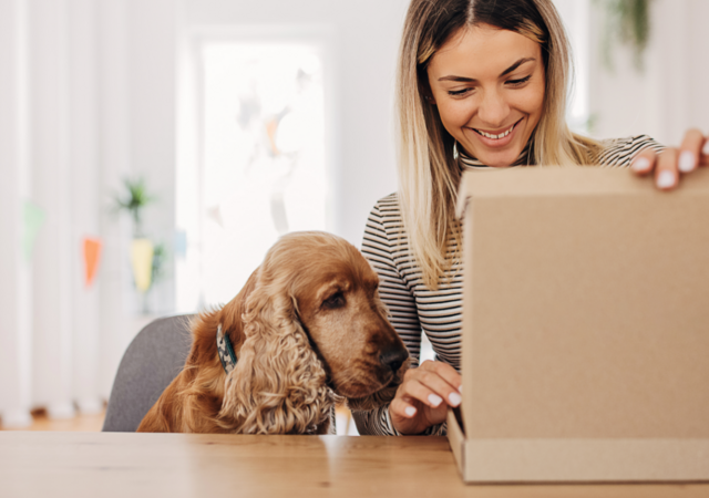 Woman sitting next to her dog while opening a package