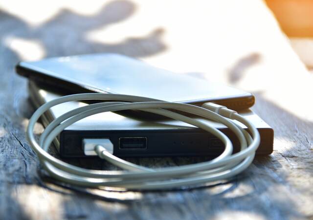 Close-up of mobile phone connected to portable charger on table