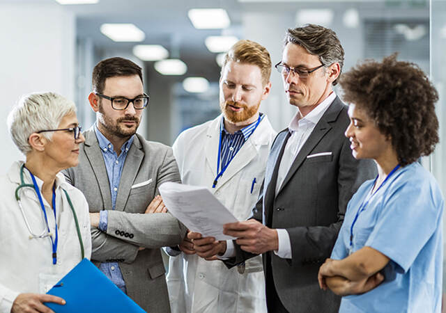 A group of five work co-workers review professional document in a medical setting