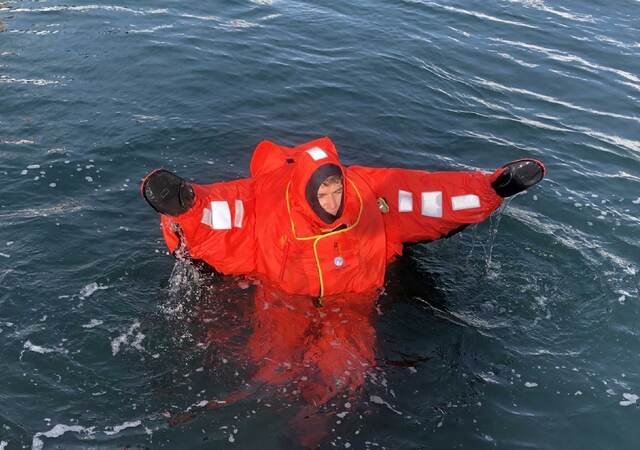 A person wearing an immersion suit and floating in water