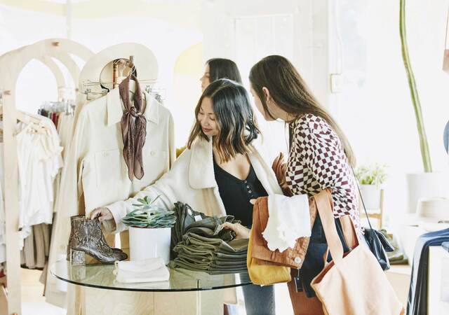 Friends admiring boots while shopping in clothing boutique