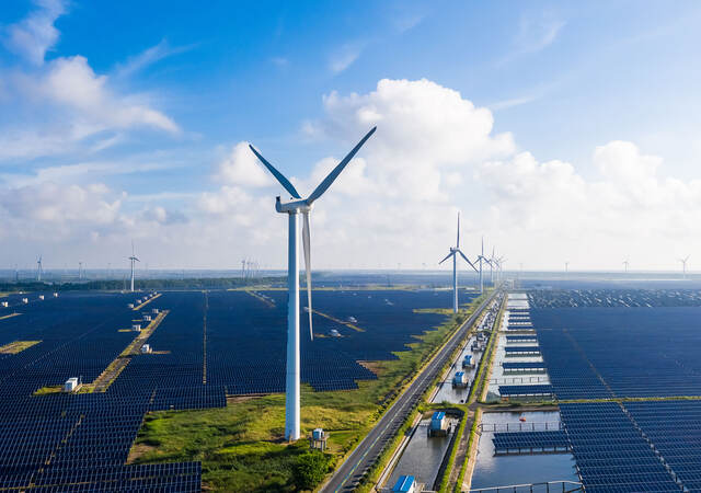 Solar power stations with wind turbines in distance