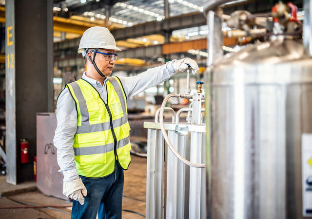 Worker operating a gas tank in a factory.  