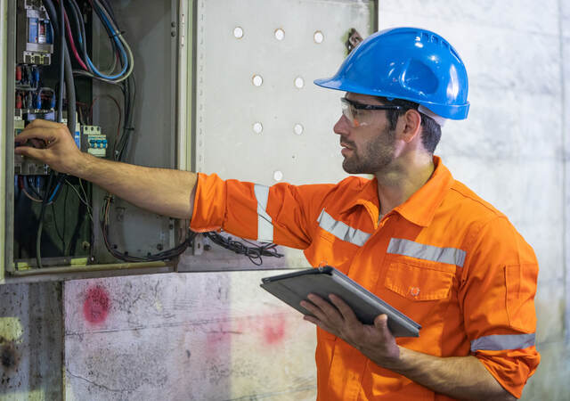 An electrician working at a circuit electrical panel.