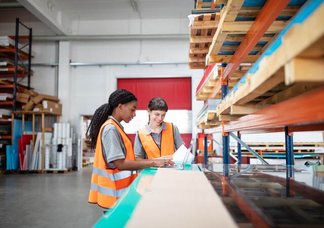 multi ethnic women workers working in a warehouse with a laptop.