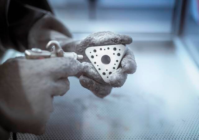 Hands holding metal 3D printed object in laboratory. 