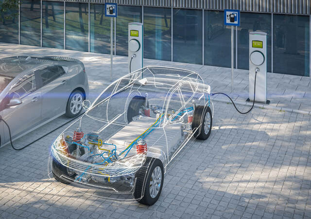 Electric car with battery visible charging at a public charger in city parking lot