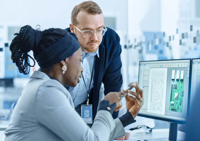 Colleagues discuss microchips in engineering workspace 