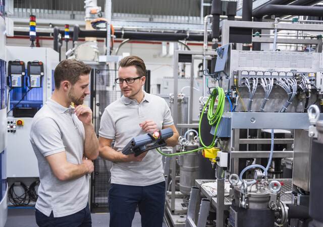 Two men with a control system on factory shop floor.