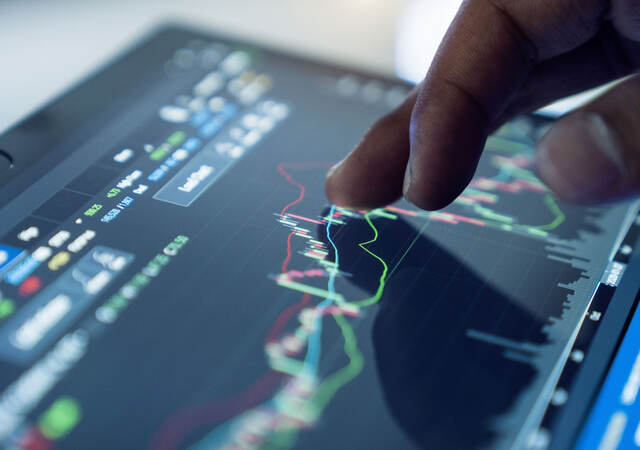 A hand interacts with a screen displaying data.