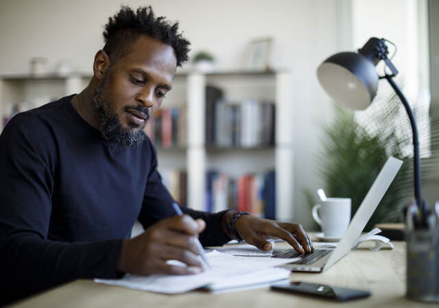 Person writing notes while sitting at a desk