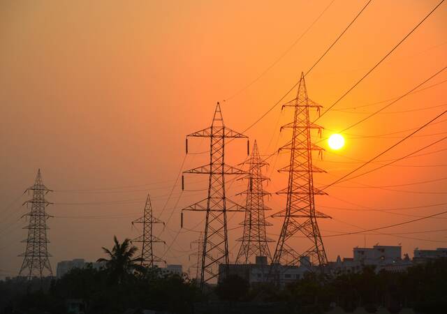 Sunset behind electrical power lines and buildings.