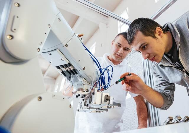 Two techs fine tuning a robotic arm