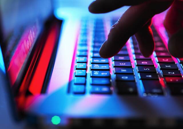 Man typing at his laptop computer at night.