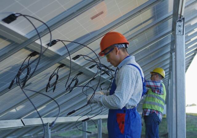 Workers connecting wires of solar panels