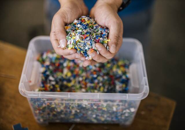 Man with container holding recycled plastic in factory