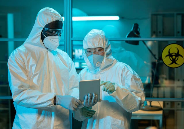 Two workers in a scientific laboratory discussing online clinical data