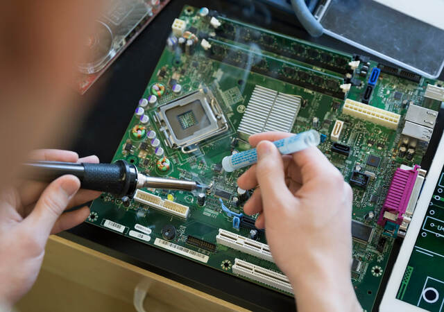 A person using a screwdriver and working on a computer board