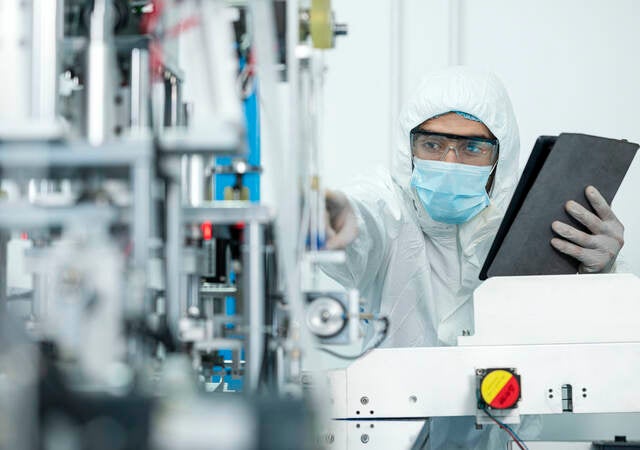 Shot of Caucasian Engineers using digital tablet for inspection quality of producing protective face mask in automated production line.