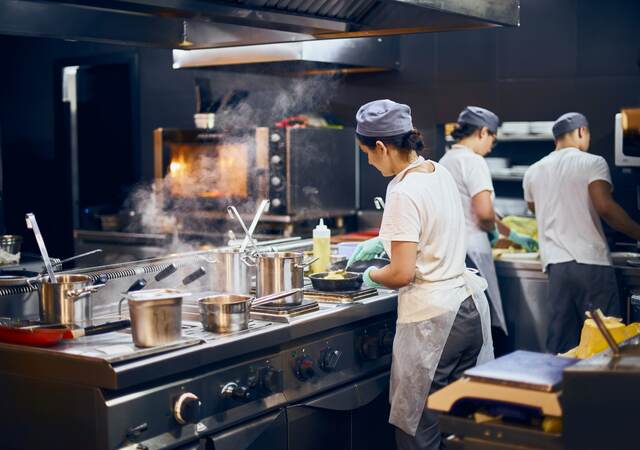 The team of cooks backs in the work in the modern kitchen, the workflow of the restaurant in the kitchen.