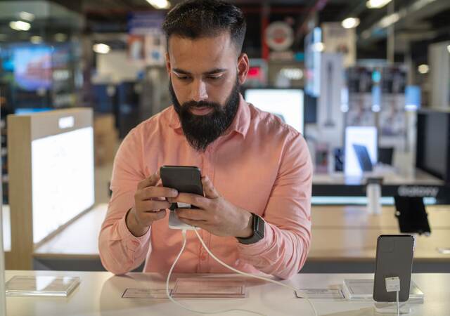 Young man testing out a mobile phone.