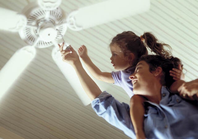 Mother and daughter turning on a ceiling fan.