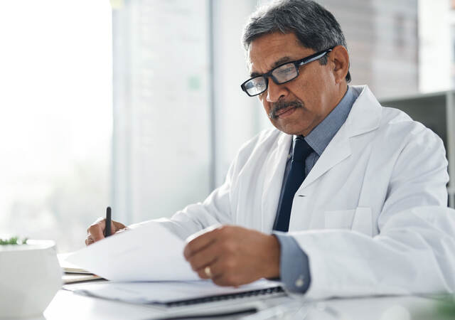 Doctor sitting at a desk doing paperwork