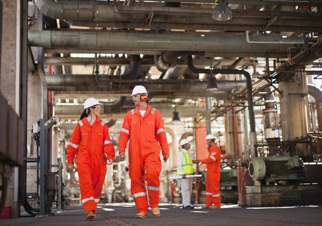 Workers wearing PPE and walking at oil refinery