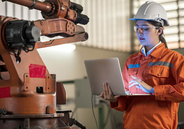 Person in factory working on a laptop