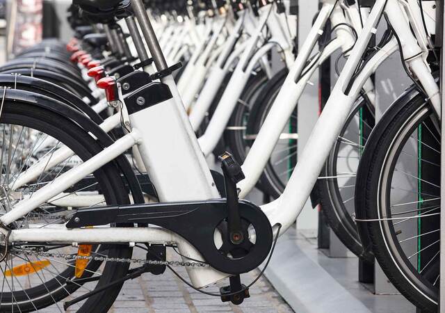 Row of white electric bikes lined up on a bike rack