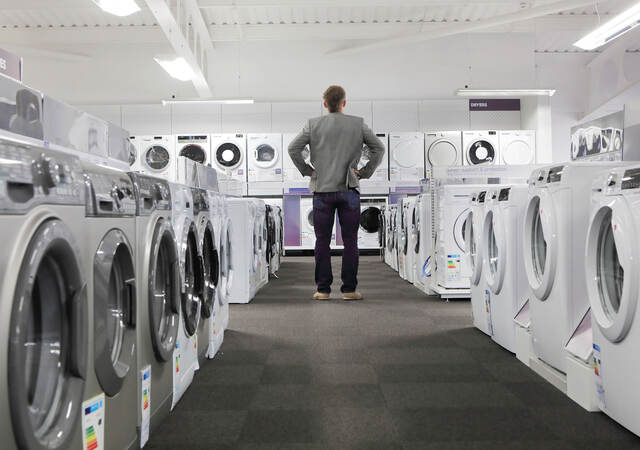 A person looking at many washers and dryers