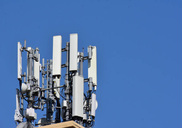 Antennas on a roof with blue sky behind it. 