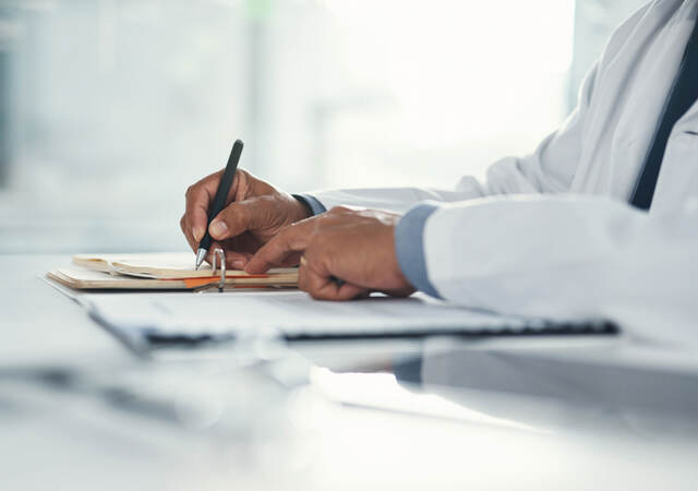 Close up of a doctor writing notes on paper 