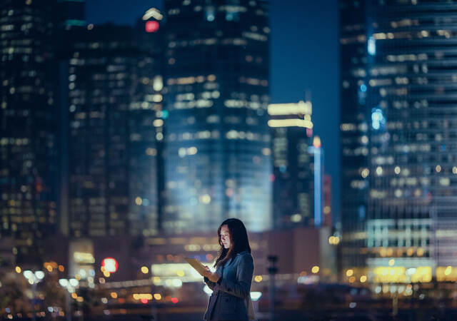 Person using a tablet at night while outside in a large city