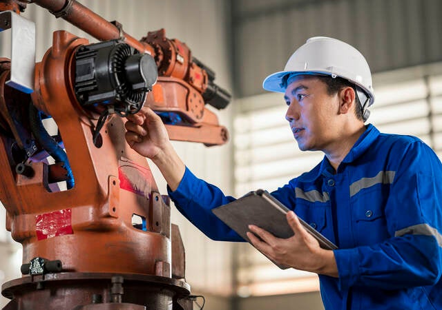 Senior Engineer testing of an industrial robot accuracy and repeatability in off and online by using digital tablet.