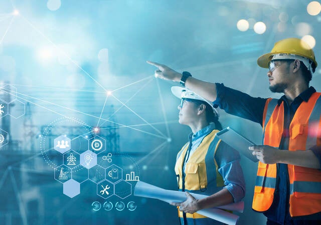 Male and female industrial engineers using tablet at power plant.