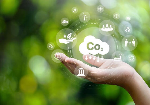 CO2 emission reduction concept in hand with environmental icons, global warming, sustainable development, connectivity and renewable energy green business background.