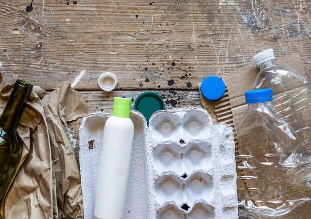 Various types of garbage for recycling on a wooden background.