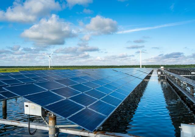 The solar photovoltaic power station on the water surface and the wind turbine in the distance.