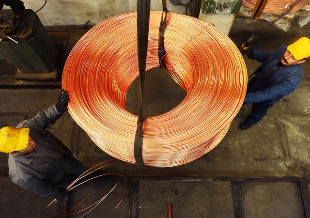 Workers moving roll of copper wire.