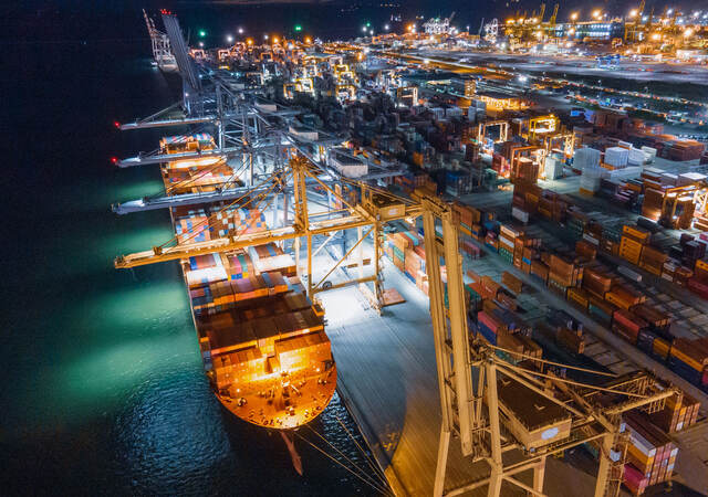 A cargo ship docked with many shipping containers