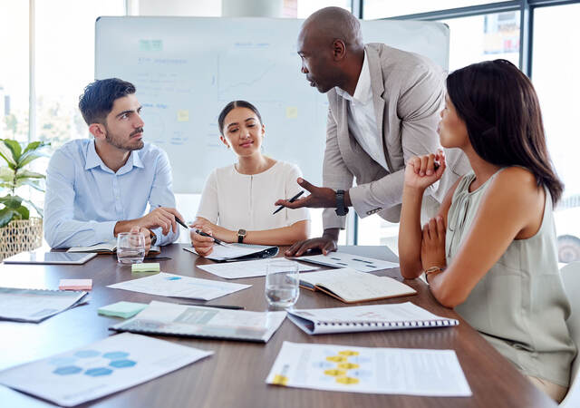 Four people attending a meeting in an office with lots of bright windows