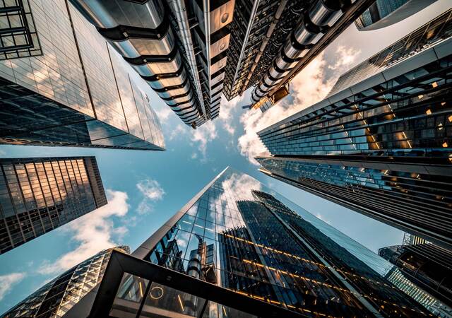 Upward view of the blue sky surrounded by towering skyscrapers