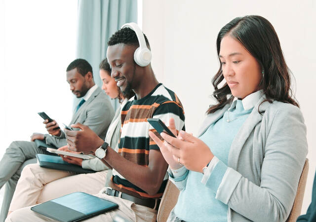 Several people in a waiting room and working on their smartphones