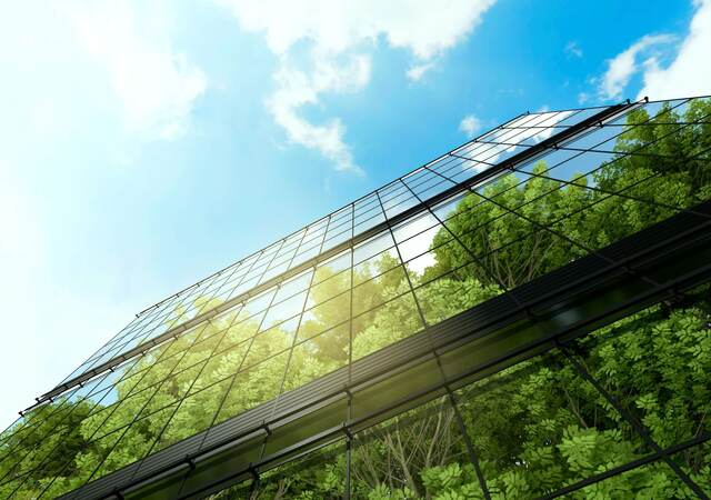 Upward view of a reflection of trees against glass skyscrapers