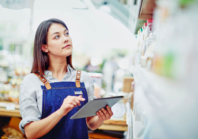 A young person holding a tablet and doing inventory in a store