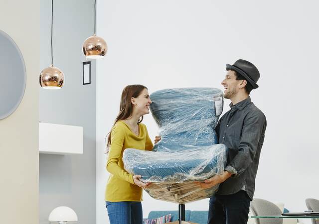 Couple carrying new arm chair out of furniture store.