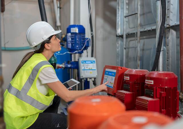 Female engineer doing quality control of water pumping engines in basement.