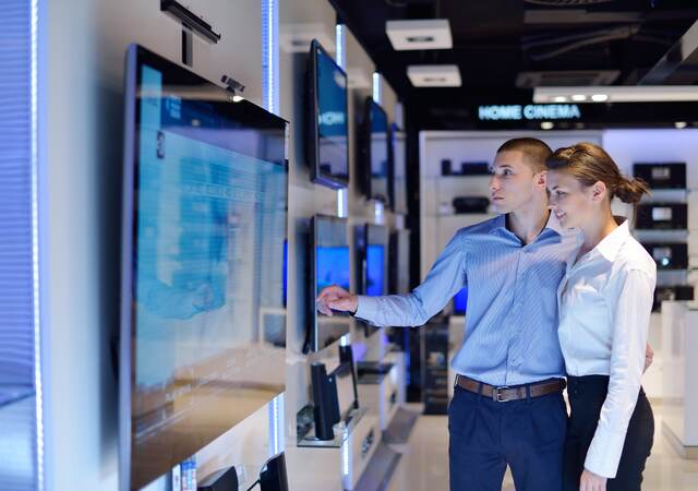 Young couple shopping for a tv in an electronic store.