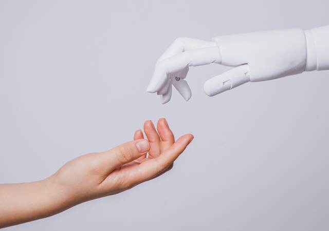 Human hand reaching for robotic hand.